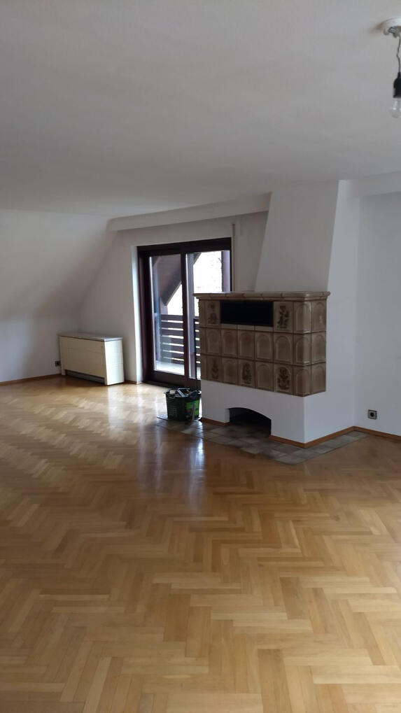 Wohnzimmer mit Kachelofen und Zugang zum Balkon